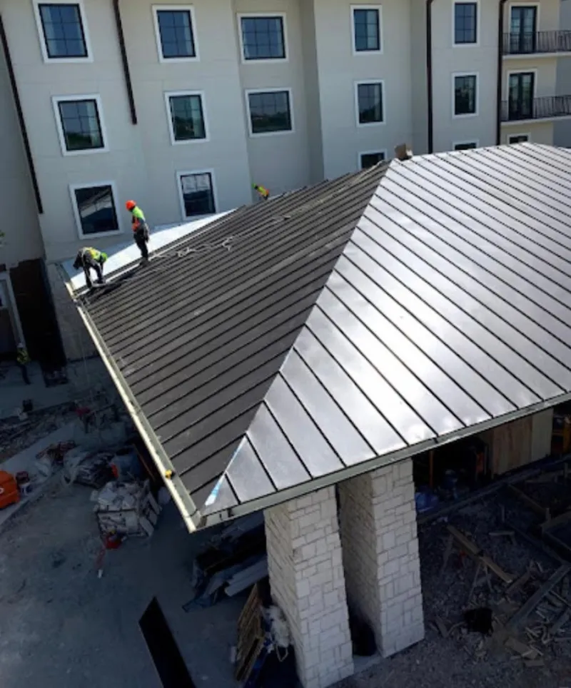 Crew installing standing seam metal roof panels on a commercial project in Severance